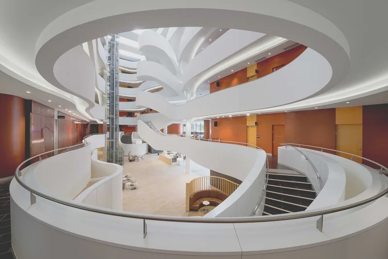 Charles Perkins Centre atrium at The University of Sydney, with sweeping white staircases and orange walls